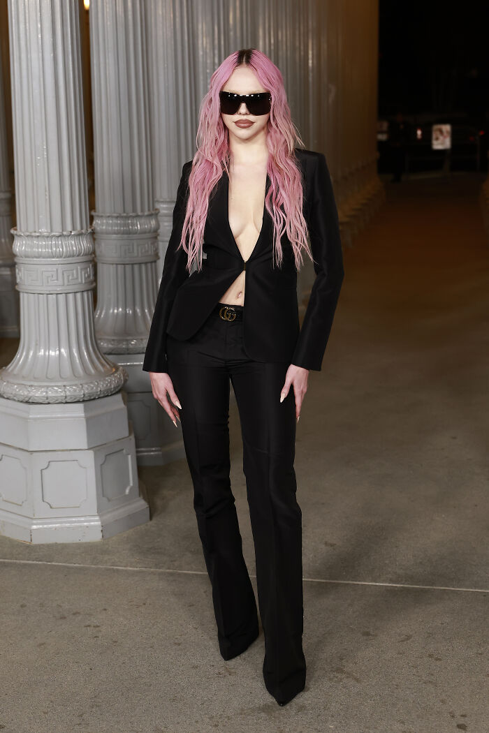 Person with long pink hair wearing sleek black outfit and sunglasses at 2025 LACMA Art and Film Gala fashion event.