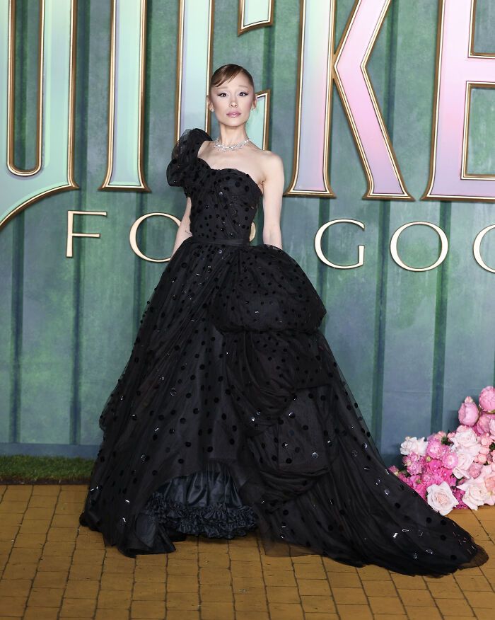 Elegant star in a black polka-dot gown posing on the red carpet at the Wicked For Good London premiere outfits event.