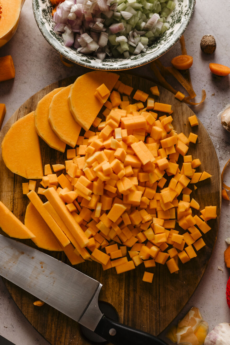 Chopped autumn vegetables on a wooden board with knife, prepping ingredients for an easy fall pie recipe.