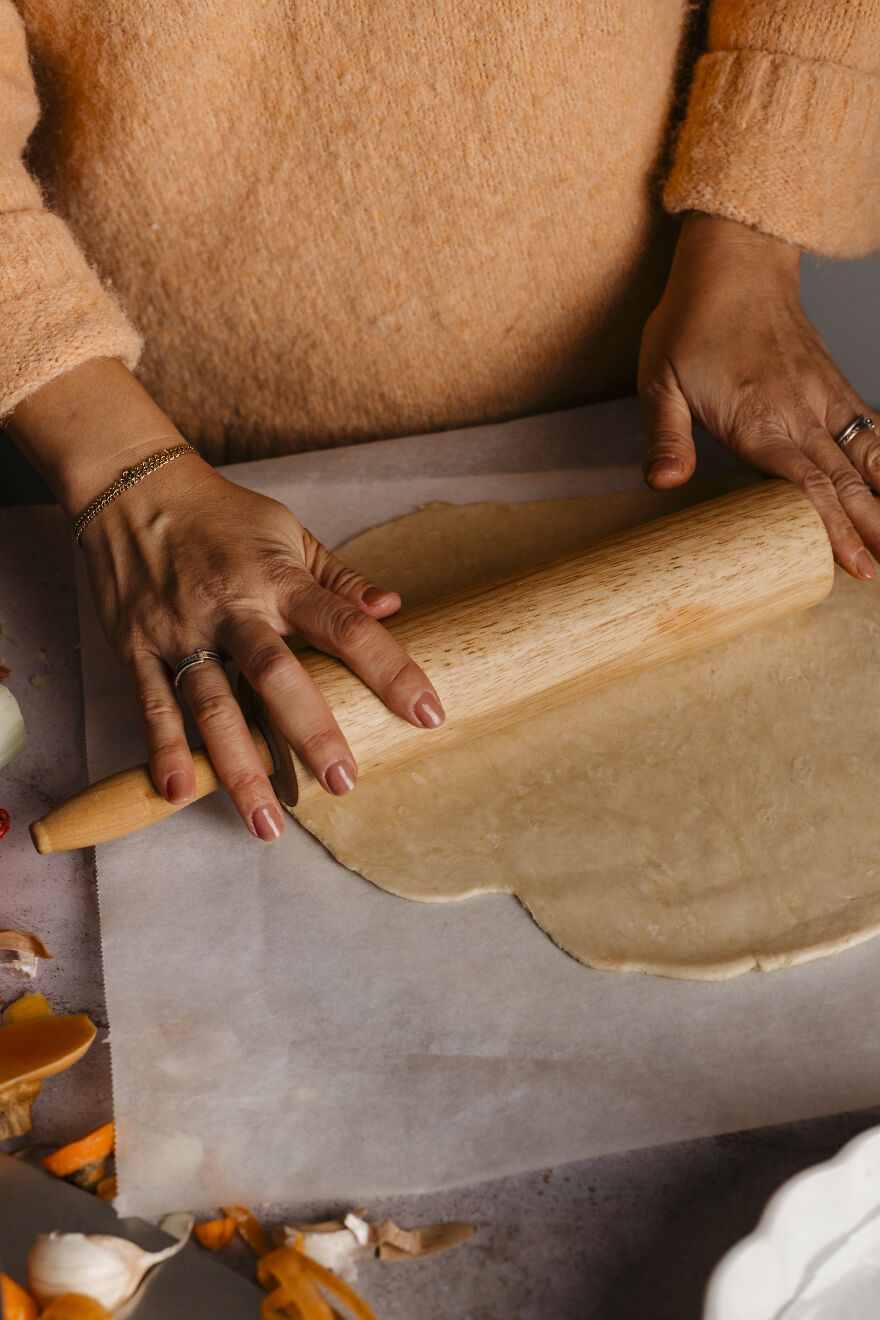 Hands rolling autumn pie dough with a wooden rolling pin, perfect for juggling motherhood and deadlines.