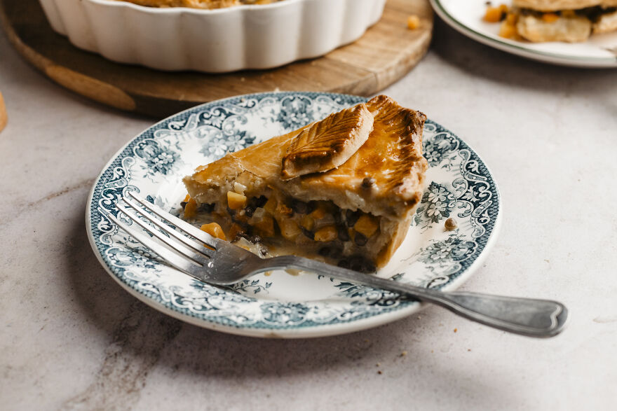Slice of autumn pie with a flaky crust, served on a decorative plate with a fork, perfect for cozy seasonal meals.