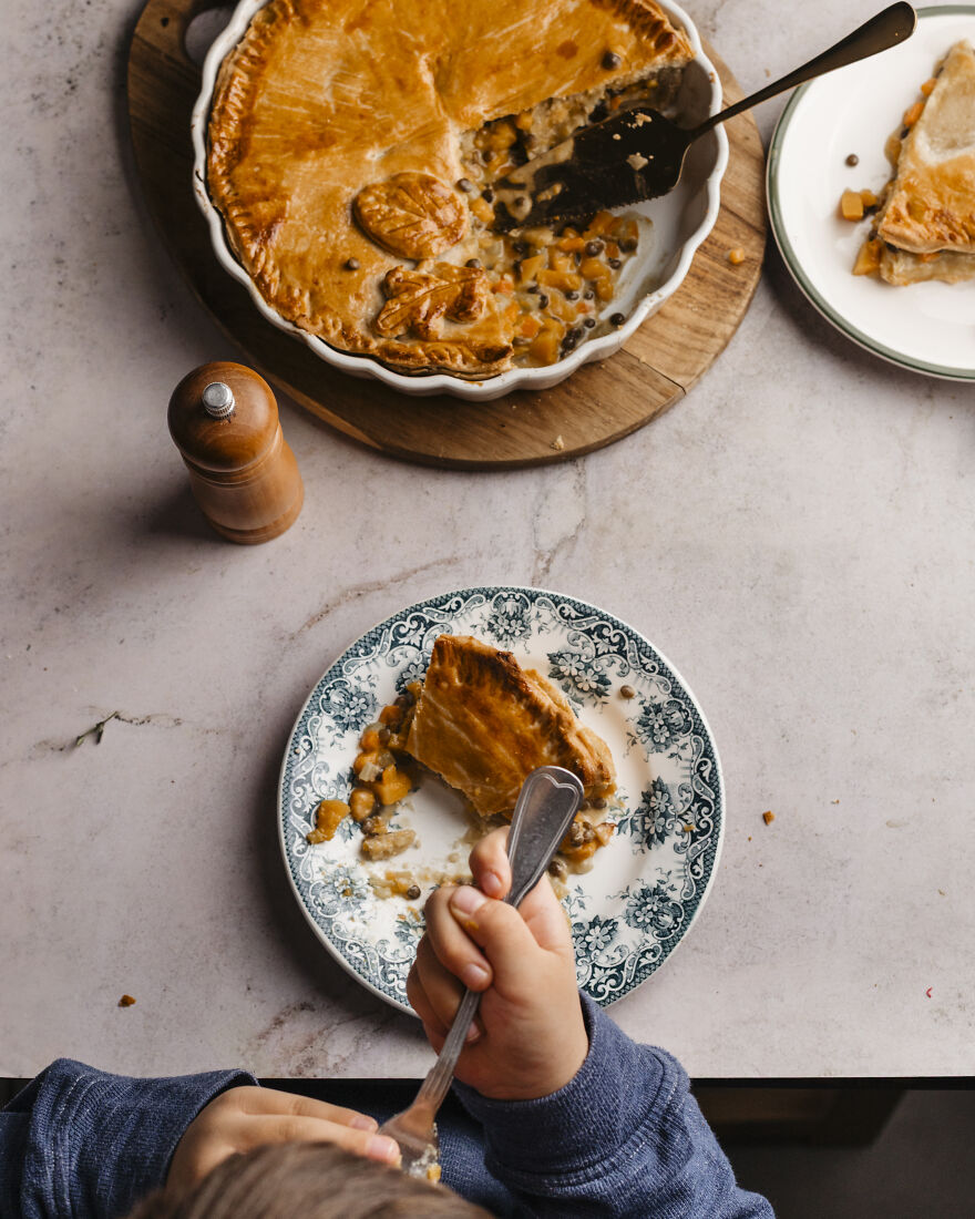 Child eating a slice of autumn pie with golden crust on a decorative plate, ideal for busy motherhood and deadlines.