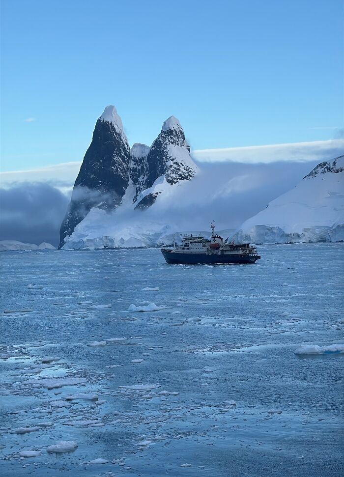 Ship sailing through icy waters with snow-covered mountains showing the scale and beauty of Antarctica landscape. Ship sailing through icy waters with snow-covered mountains showing the scale and beauty of Antarctica landscape.