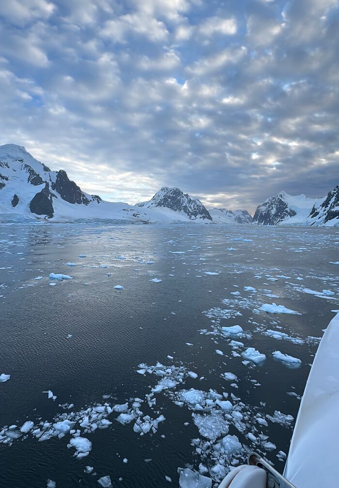 Antarctica ice-covered mountains and scattered ice floating on cold water under a cloudy sky on a serene day. Antarctica ice-covered mountains and scattered ice floating on cold water under a cloudy sky on a serene day.