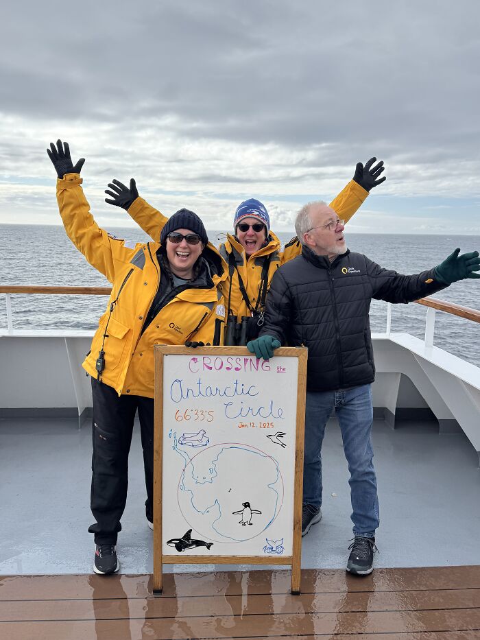 Three people celebrating crossing the Antarctic Circle on a ship deck, showcasing the scale and beauty of Antarctica. Three people celebrating crossing the Antarctic Circle on a ship deck, showcasing the scale and beauty of Antarctica.