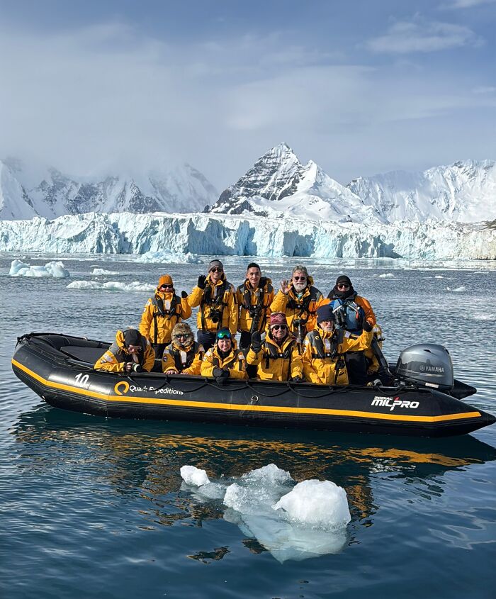 Group of adventurers in yellow jackets on a boat surrounded by Antarctica’s vast icy landscape and towering snow-covered mountains. Group of adventurers in yellow jackets on a boat surrounded by Antarctica’s vast icy landscape and towering snow-covered mountains.