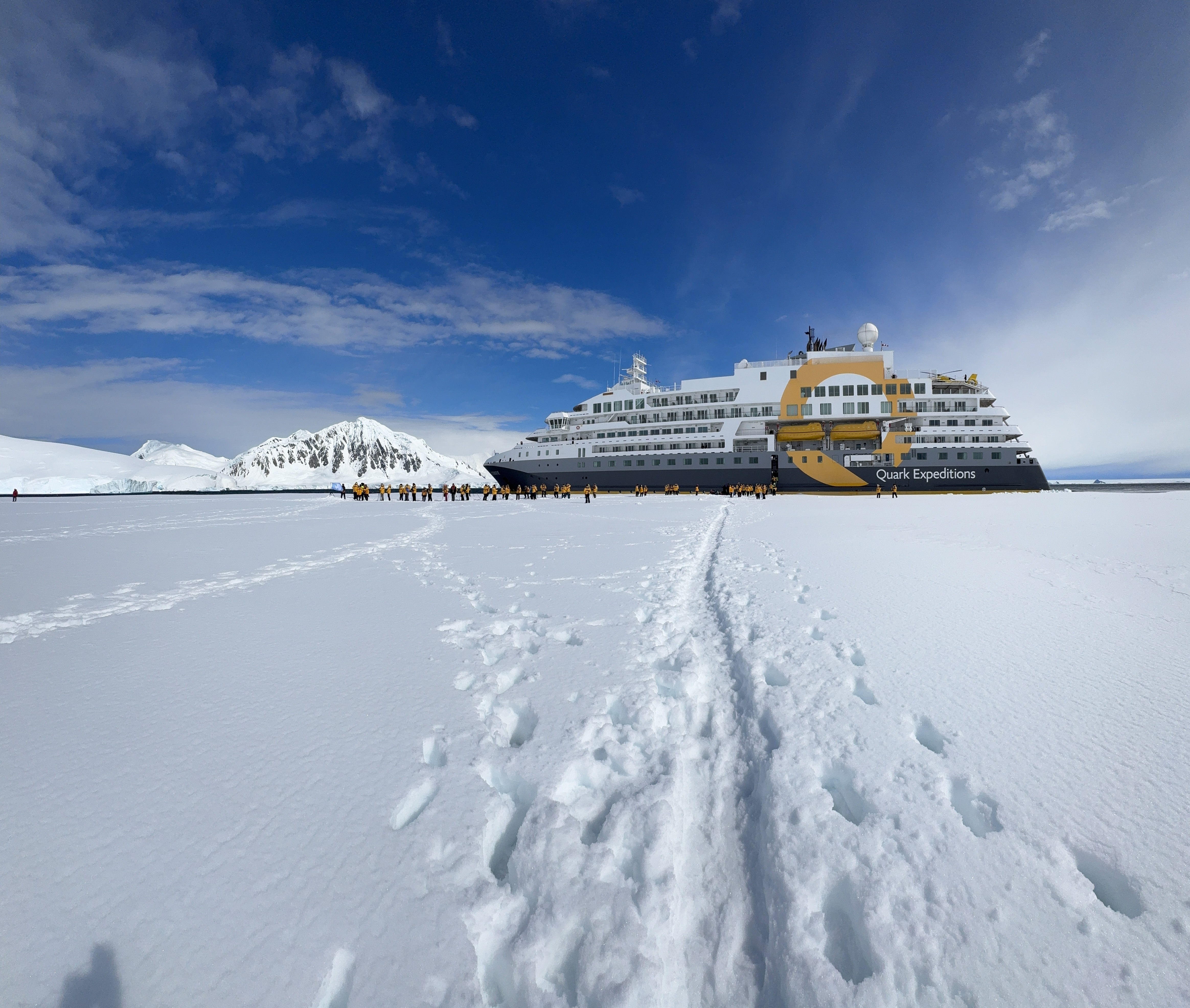 Expedition ship docked on icy Antarctic shore with tourists exploring the vast scale and beauty of Antarctica landscape Expedition ship docked on icy Antarctic shore with tourists exploring the vast scale and beauty of Antarctica landscape
