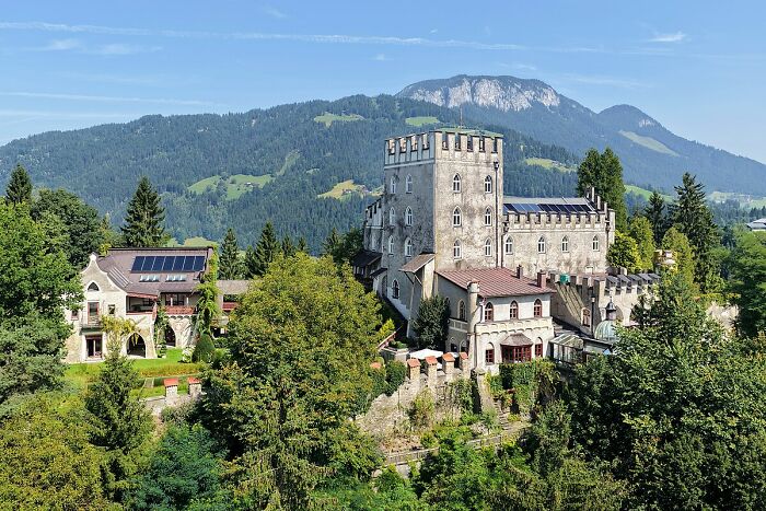 Historic castle surrounded by lush greenery and mountains, showcasing a scene from hilarious historical events.