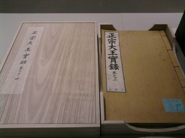 Wooden box and ancient book with Asian characters, representing historical artifacts linked to hilarious historical events.