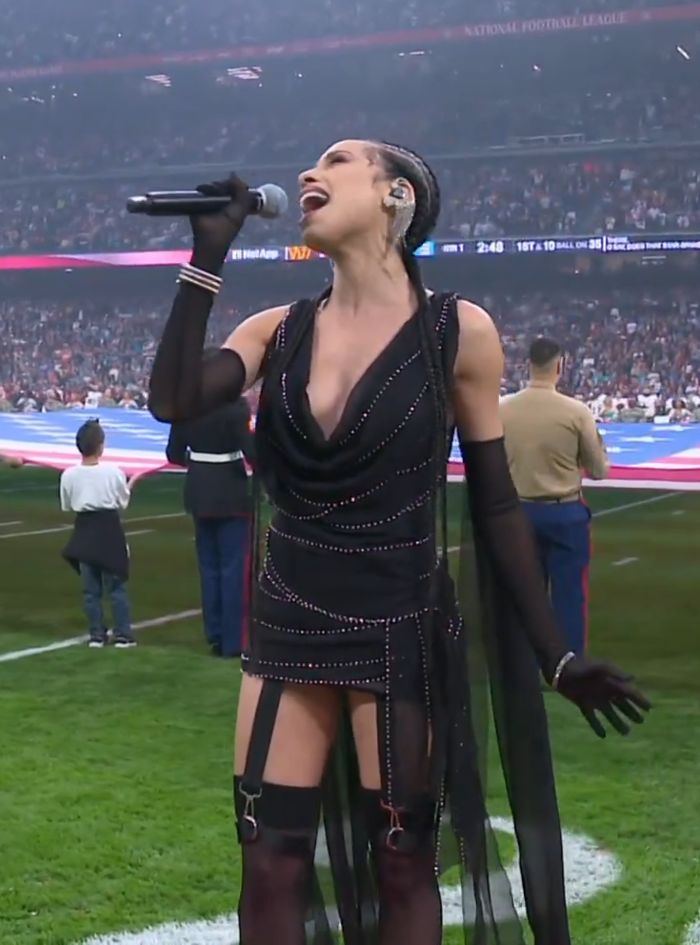 Singer performing US national anthem at NFL game wearing a controversial and disrespectful outfit during the event.