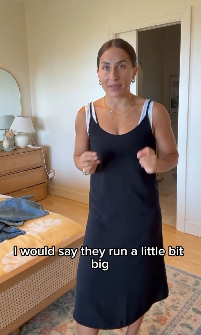 Woman in a black dress discussing Mormon women&rsquo;s reaction to more revealing sacred underwear in a casual bedroom setting.