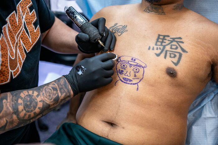 Tattoo artist working on a man's regretful chest tattoo as he struggles with depression and emotional pain.