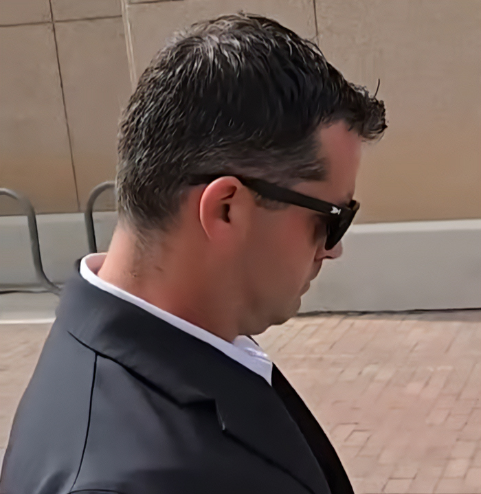 Man wearing black sunglasses and suit walking outside, related to dad who fatally left 2YO daughter in car case Man wearing black sunglasses and suit walking outside, related to dad who fatally left 2YO daughter in car case