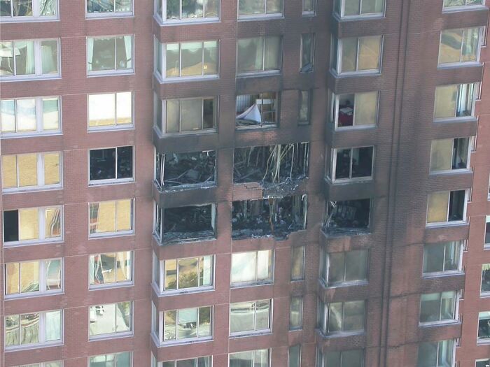 High-rise building with extensive fire damage, showcasing charred windows and burned interior rooms in an urban area.