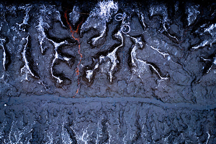 Aerial view of volcanic lava formations and a bicycle on c*****d earth showcasing award-winning nature photography.