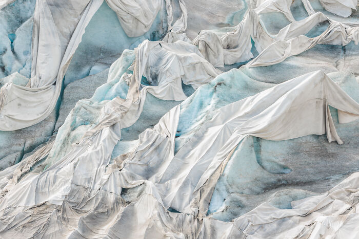 Abstract glacier surface covered with white protective sheets showcasing award-winning nature photos' magic.