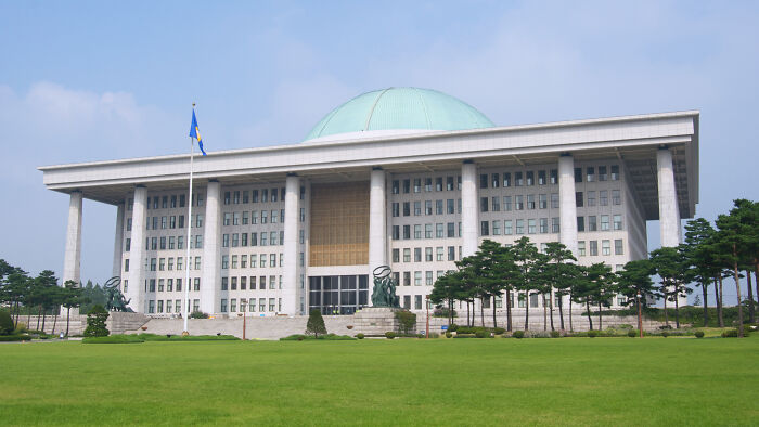 South Korean government building with green lawn under blue sky, related to world&rsquo;s smartest man seeking US asylum news.
