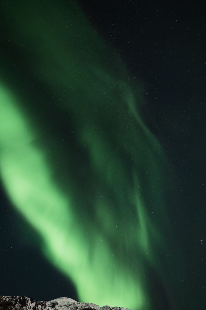 Green northern lights dancing over a snowy landscape, showcasing the best places and times to see the northern lights.
