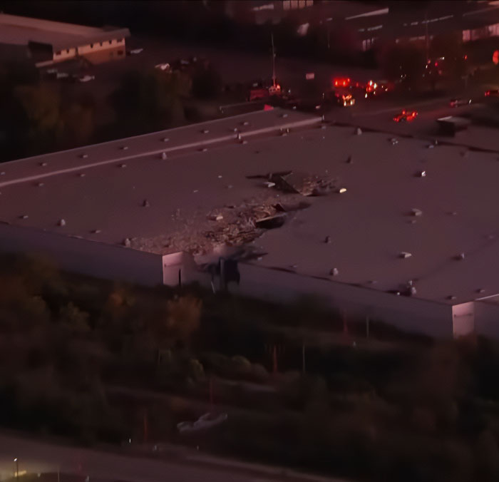 UPS plane crash debris on warehouse rooftop with emergency vehicles and responders on site at dusk