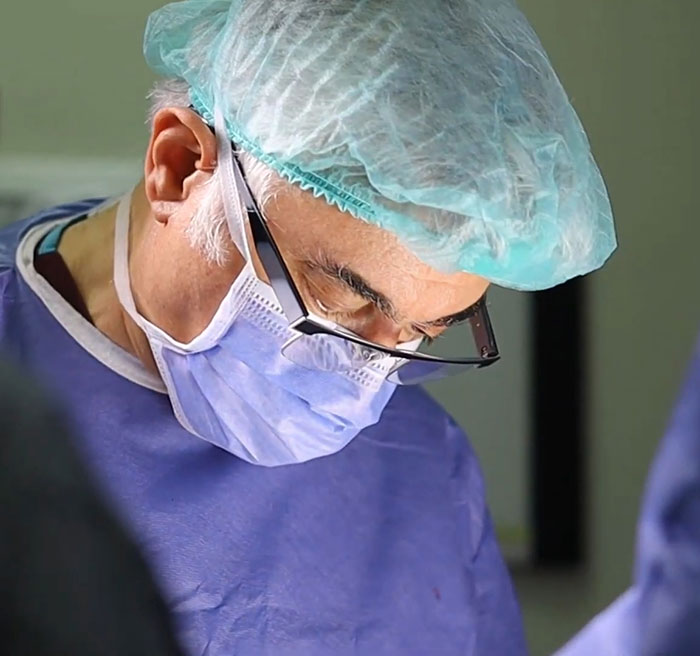 Expert surgeon wearing surgical cap and mask focused during plastic surgery procedure in modern operating room