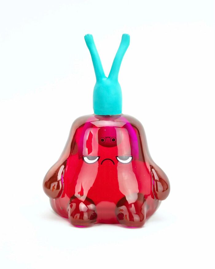 Glossy quirky sculpture with a red body and blue antennae, showcasing unique personality and expressive face details.