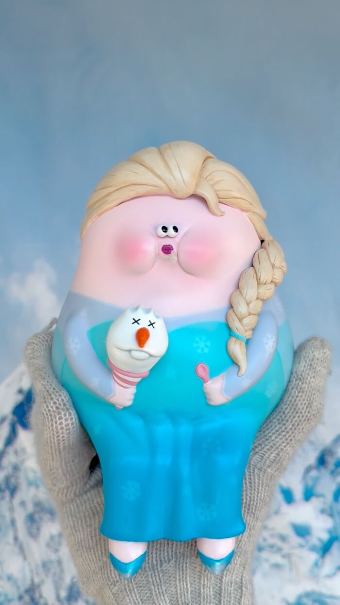 Quirky sculpture with blonde braid and blue dress holding a small snowman, showcasing artist made personality-filled art.