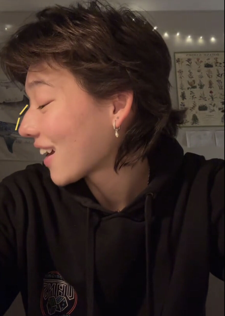 Young person smiling and looking to the side, embracing perfect imperfections in a cozy indoor setting.