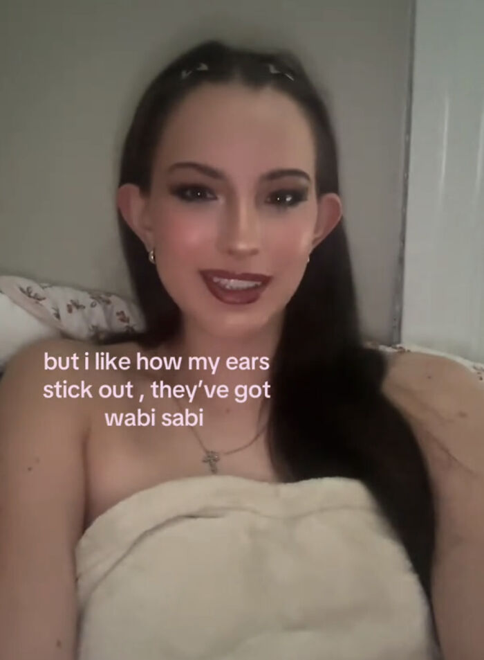 Mujer sonriente celebrando lo que la hace única, destacando sus orejas grandes como parte de su belleza personal.