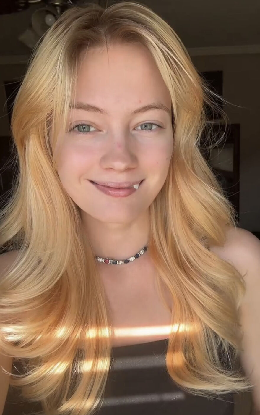 Young woman with blonde hair smiling confidently, embracing her perfect imperfections in a wholesome self-acceptance trend.