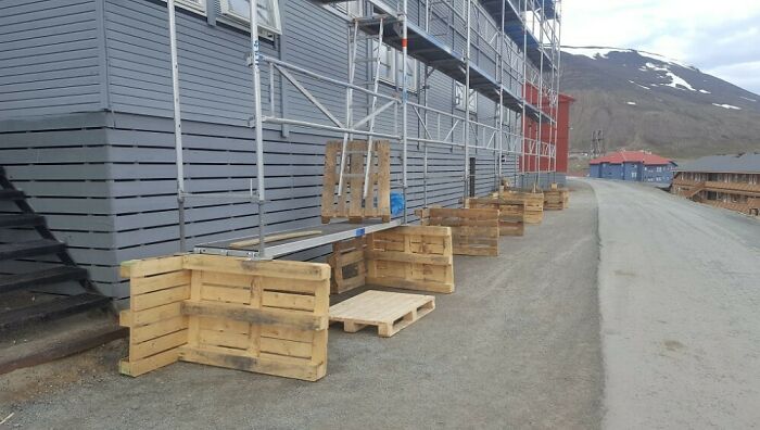 Wooden pallets arranged as makeshift benches outside a building, illustrating funny examples of people not even trying.