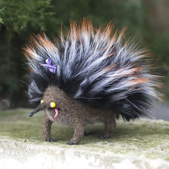 Handmade creature toy with fluffy textured fur and quirky facial features displayed outdoors on stone surface.
