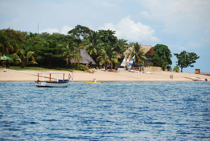 A remote tropical beach with small boats and huts surrounded by palm trees, highlighting the poorest country in the world.