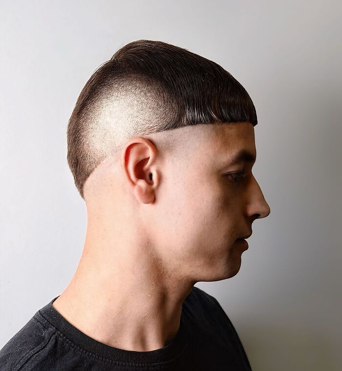 Young man with bold barber haircut featuring a sharp geometric fade and textured cropped fringe on side profile.