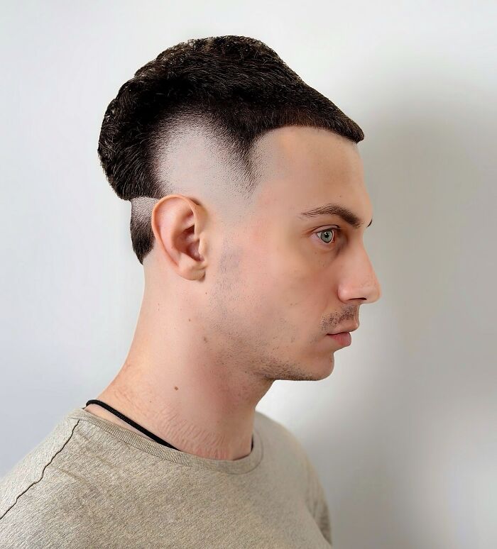 Young man with a bold barber haircut featuring a sharp fade and a unique textured top hairstyle in profile view