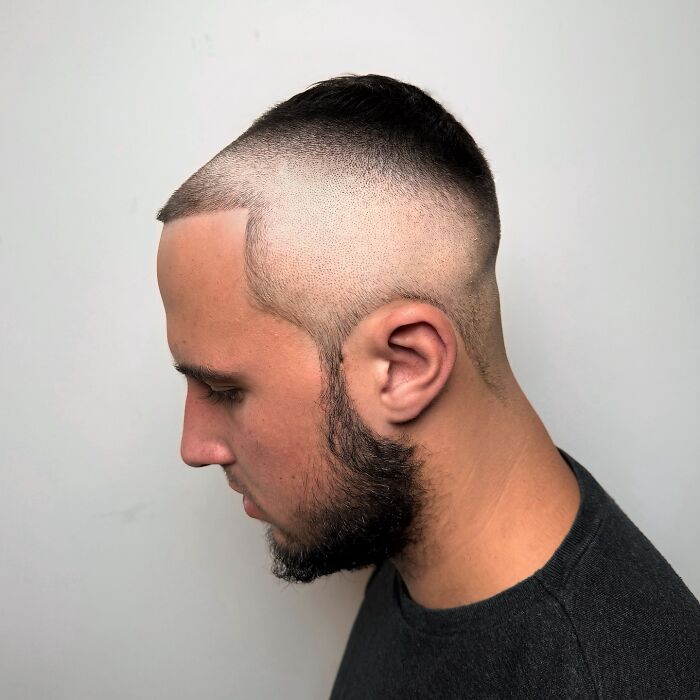 Close side view of a man with bold barber haircuts featuring a unique high fade and sharp hairline design.