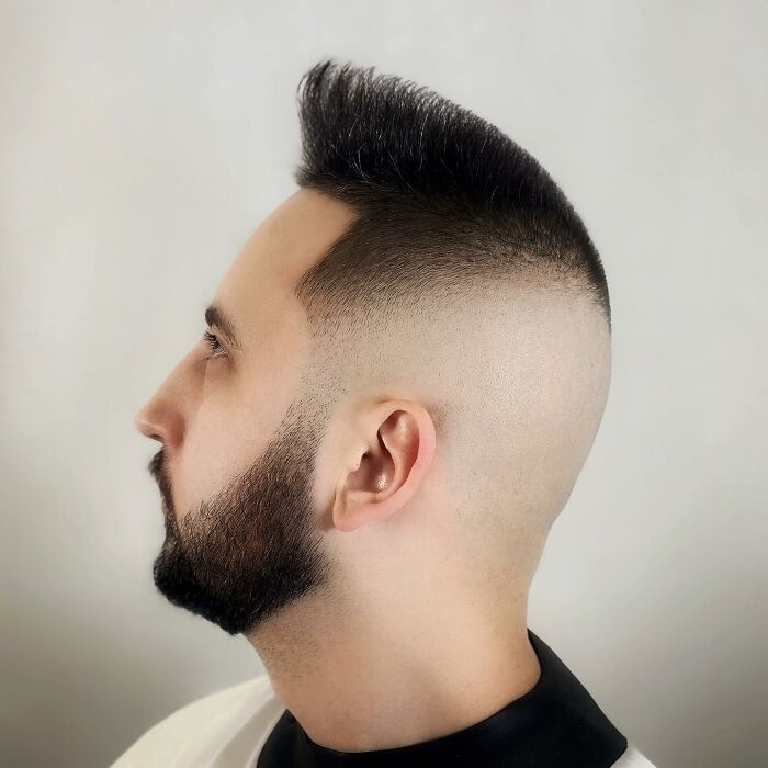 Side view of a man with a bold barber haircut featuring a high fade and styled top hair.