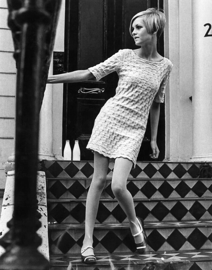 Black and white photo of a style icon in a textured mini dress, influencing fashion trends and inspiring mood boards worldwide.