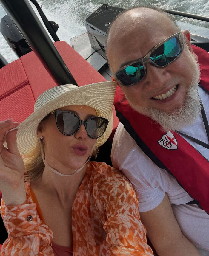 Singer wearing sunglasses and hat taking a selfie with a man on a boat, relating to Malaysia&rsquo;s ex-king divorce news.