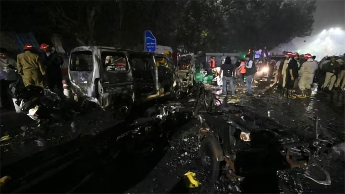 Burned vehicles and emergency responders at the scene of a horror car blast shaking the capital city at night.