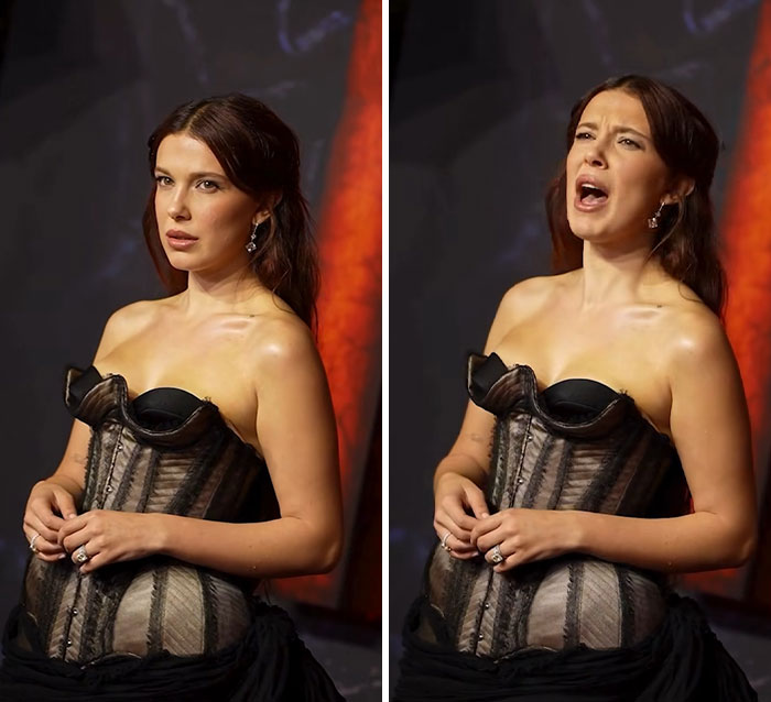 Woman wearing black lingerie with a train posing at a red carpet event with dramatic lighting background.