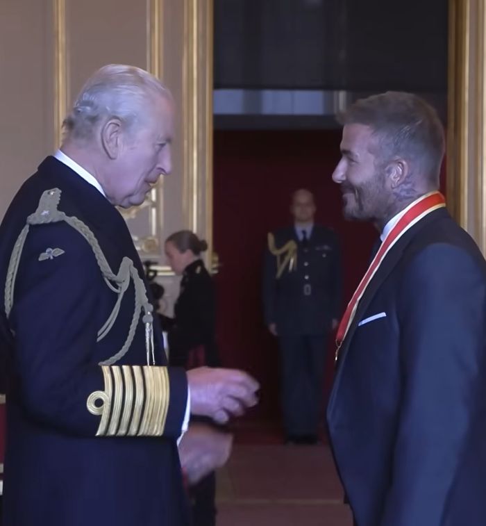 King Charles presenting David Beckham with a medal during a formal ceremony after receiving his sir title. King Charles presenting David Beckham with a medal during a formal ceremony after receiving his sir title.