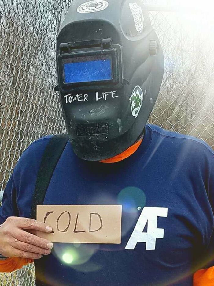 Man wearing welding helmet and holding cold sign, showcasing wholesome moments proving men never grow up.