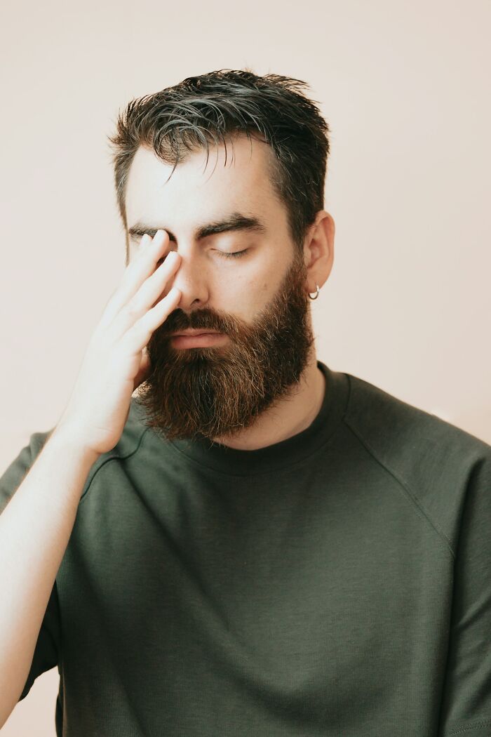 Bearded man with eyes closed, touching his face, illustrating mysterious medical issues and diagnosis relief.