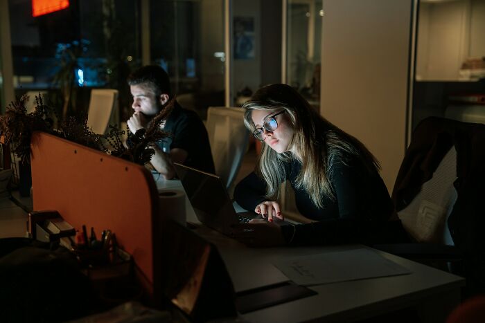 Two internet users working late in an office, focused on laptops, depicting common misconceptions about internet scams.