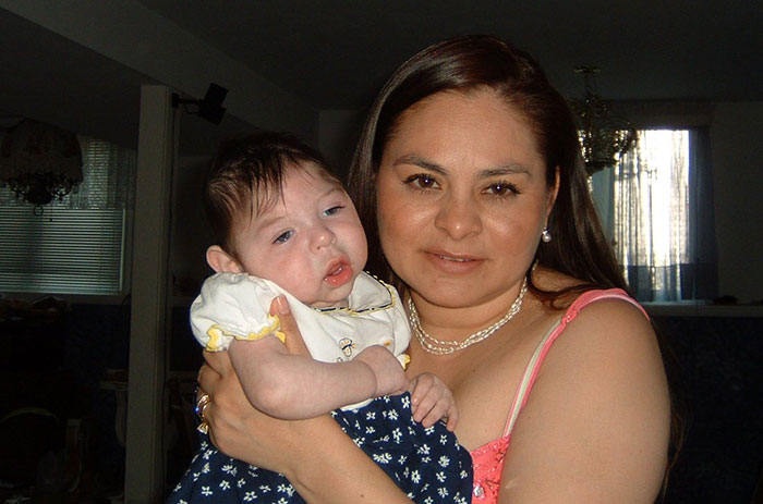 Woman holding baby born without most of her brain, highlighting rare medical condition with family in home setting