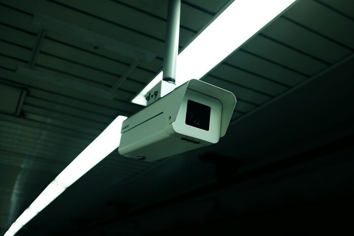 Surveillance camera mounted on ceiling with dark background, capturing eerie and unsettling footage in low light conditions.