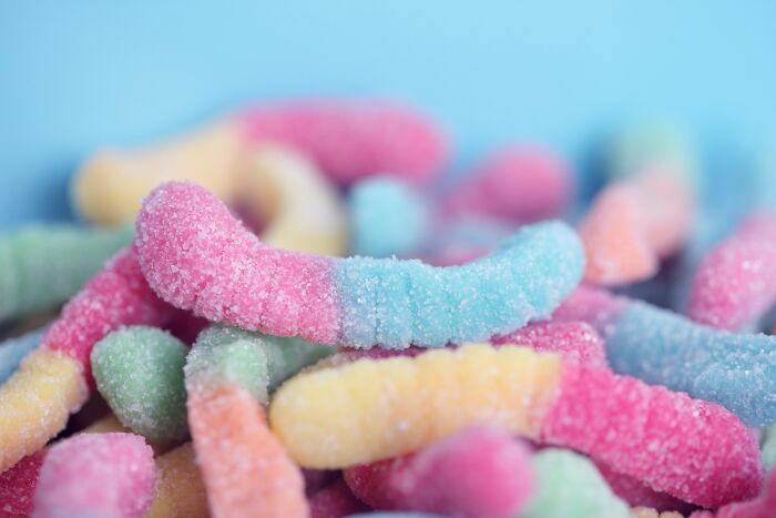 Close-up of colorful sour gummy worms covered in sugar crystals, highlighting comically absurd facts about candy treats.