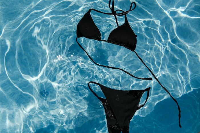Black bikini floating in clear water, illustrating the etymology of common words related to swimwear and summer.