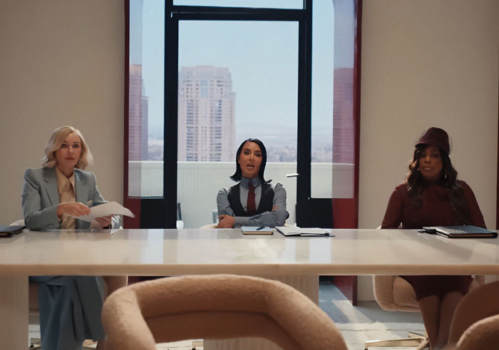 Three women sitting at a modern conference table during the All's Fair premiere with Kim Kardashian in a bright office.