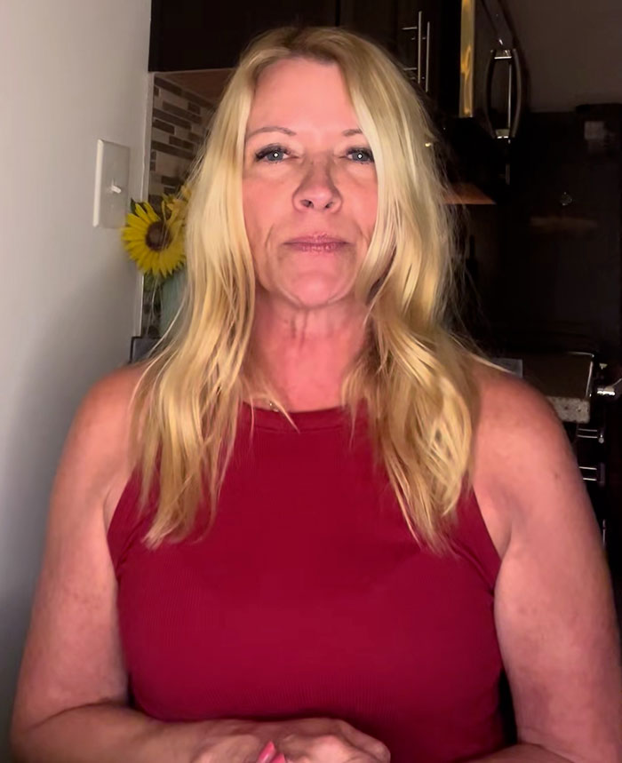 Middle-aged woman with long blonde hair wearing a red sleeveless top discussing bearded trans man in women&rsquo;s restroom debate